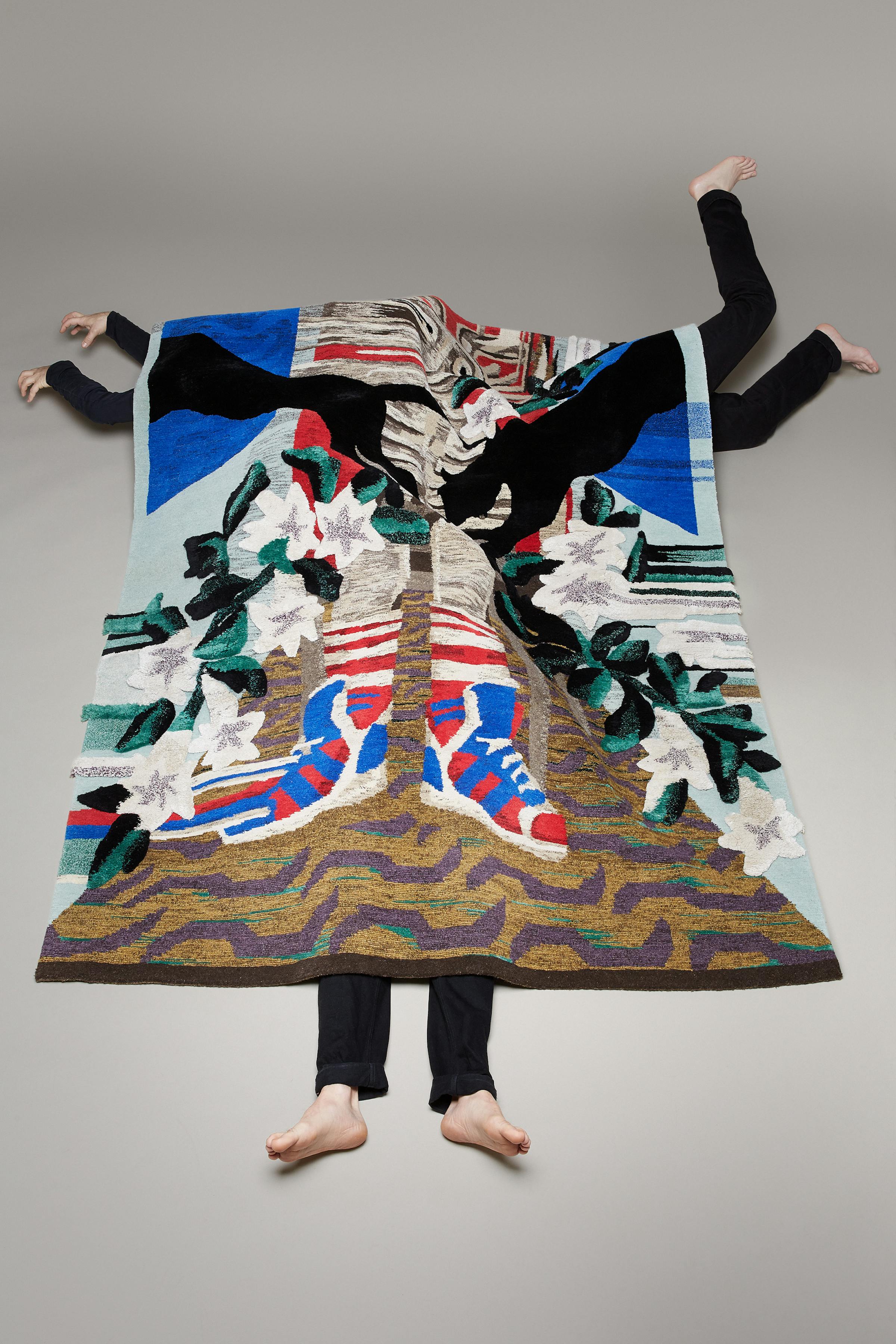 Three men in black trousers crawl under a large carpet with a panther design.