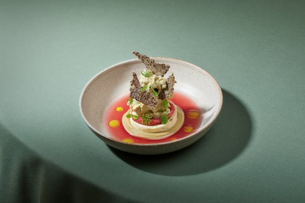 Plate with dessert - a pistacchio ice cream in a rhubarb coulis on a green table cloth