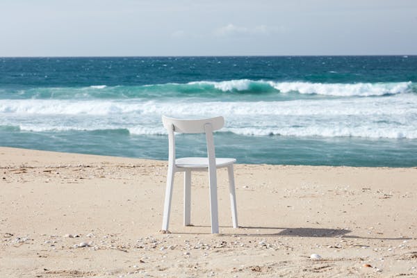 A white All Plastic Chair by Jasper Morssion on the beach overlooking the blue sea