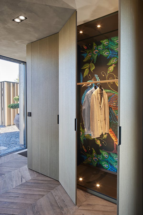 Wardrobe with a coloured fabric wallpaper with a peacock pattern