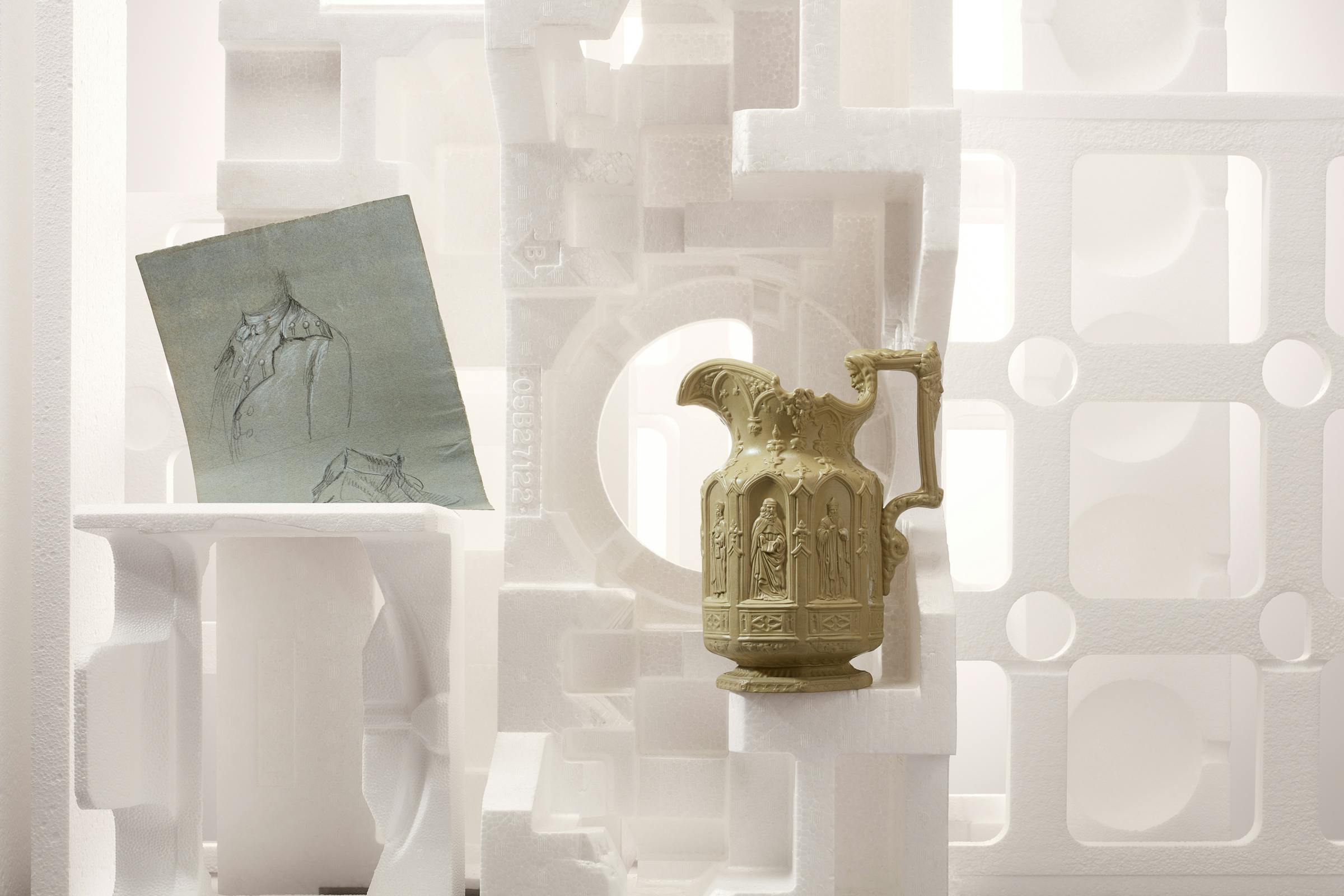 A classic pitcher in beige color standing in a set design made of white styrofoam objects