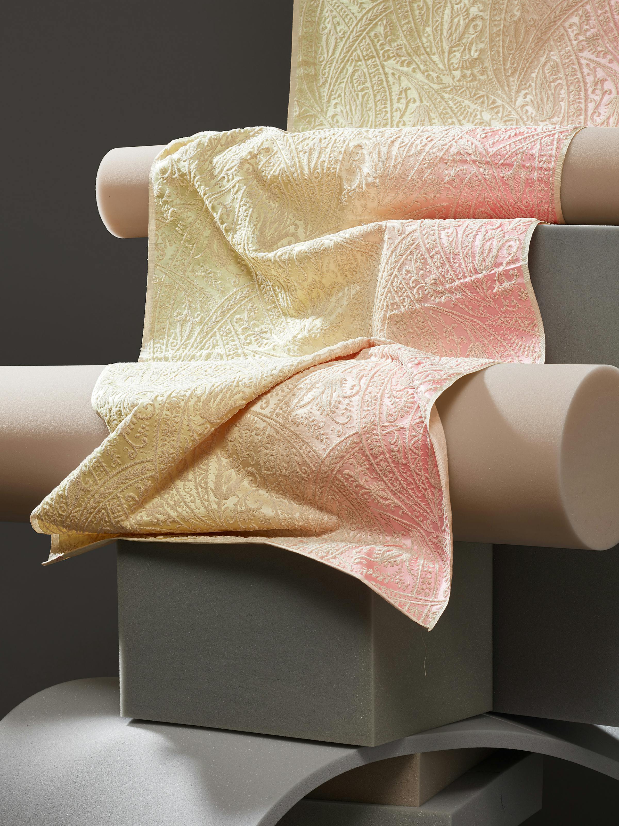 Close-up of a 19th-century fabric with a colour gradient from yellow to pink on grey foam