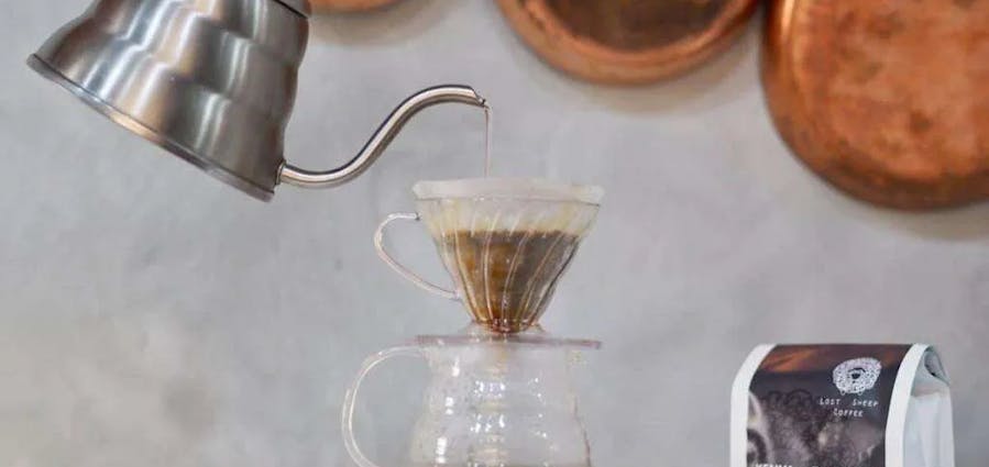 A swan neck kettle poring water over a v60 filter.