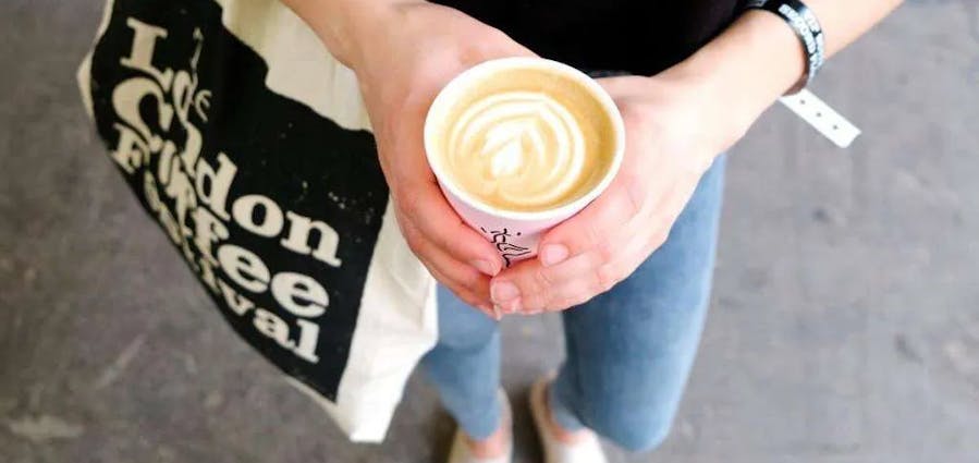 A person holding a cup of coffee at The London Coffee Festival
