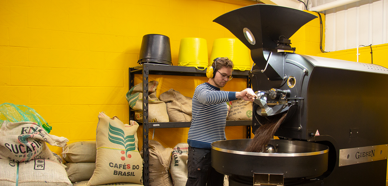 Person opening hopper from roaster at Lost Sheep Roastery 