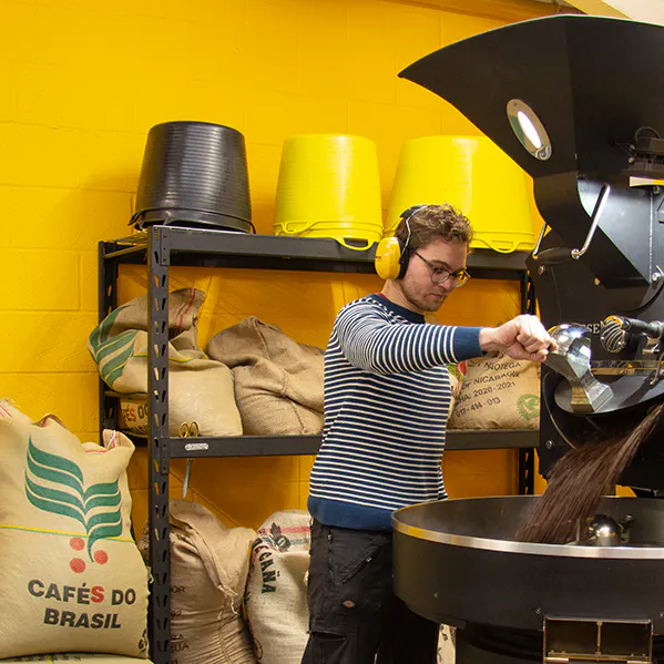 Person opening hopper from roaster at Lost Sheep Roastery