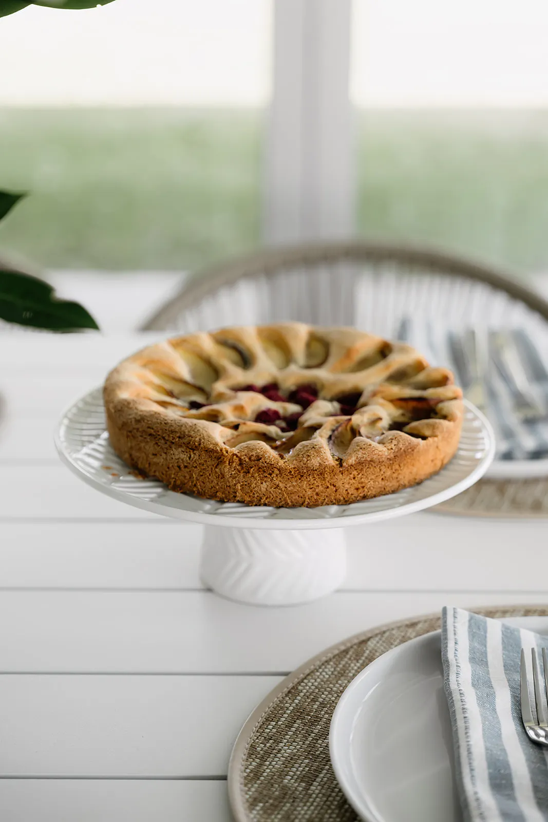 Image of a peach cake on a stand on a table, beachy vibe inside a pool house.