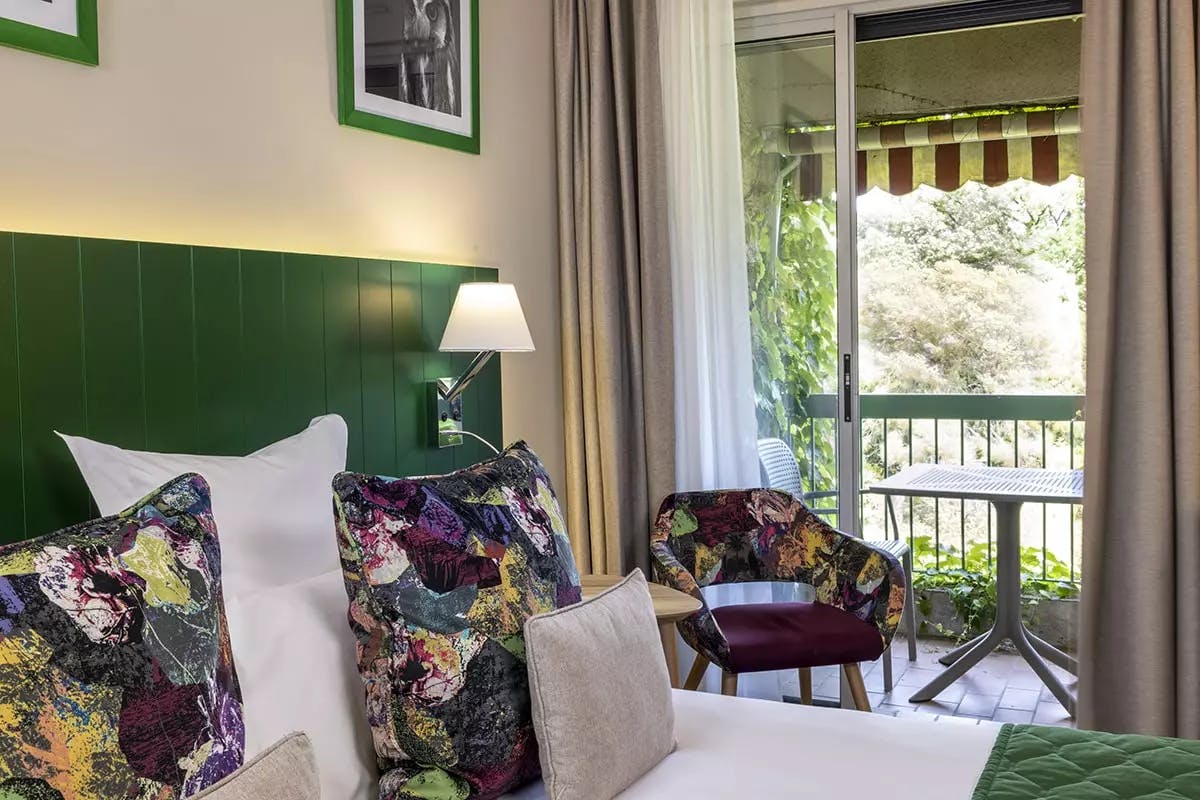 Lit dans une chambre d’hôtel avec une tête de lit verte | Lou Paradou Hôtel | Gréoux-les-Bains