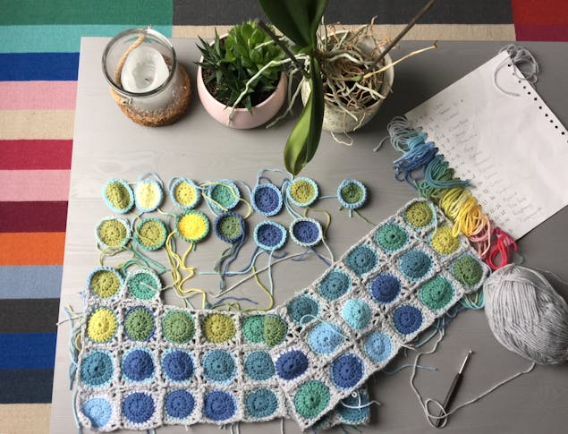 Multicoloured crochet square blanket in progress with labelled colour notes