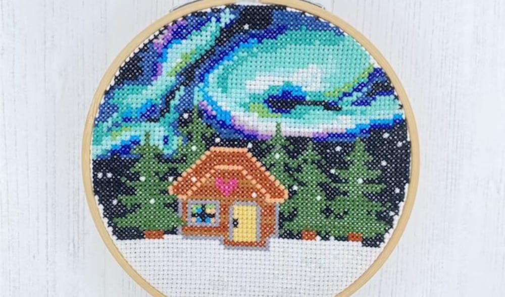 Winter cross stitch with house under Northern Lights