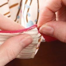 hand stitching the edges of the zip