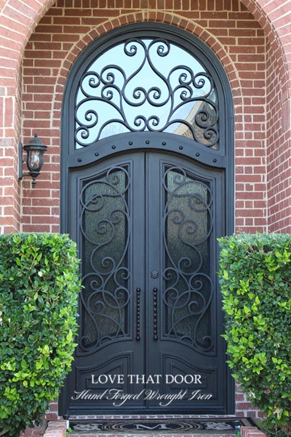 Regal iron door and transom combination, making a bold statement with its intricate craftsmanship and elegant design.