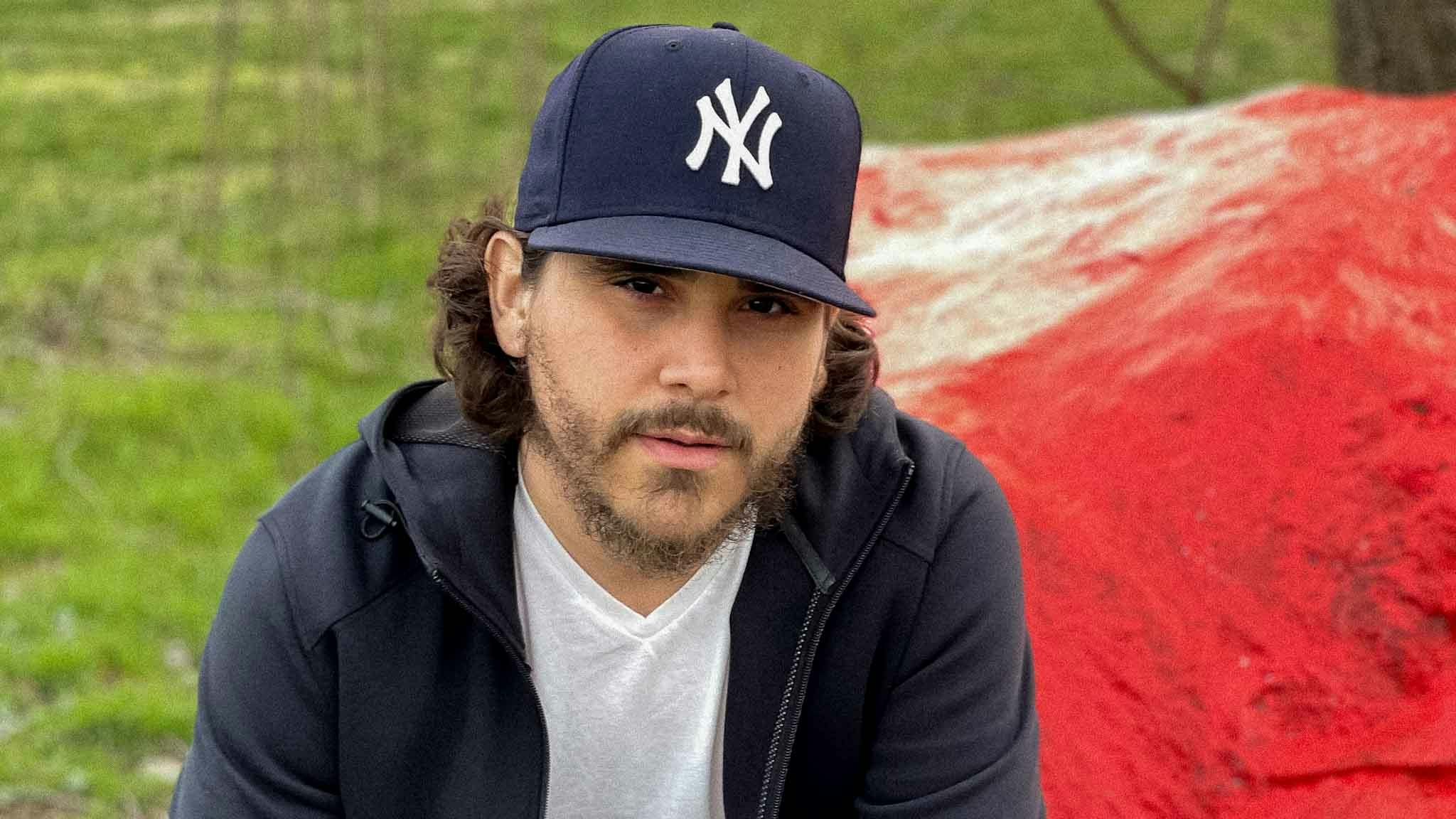 Louie C Rhymes sitting outside with a New York Yankee's Hat.