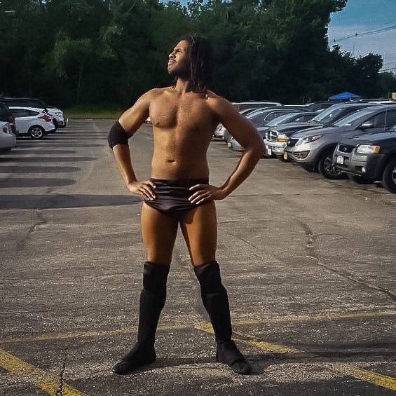Godcloud standing in a carpark wearing nothing but underwear, socks and shoes.