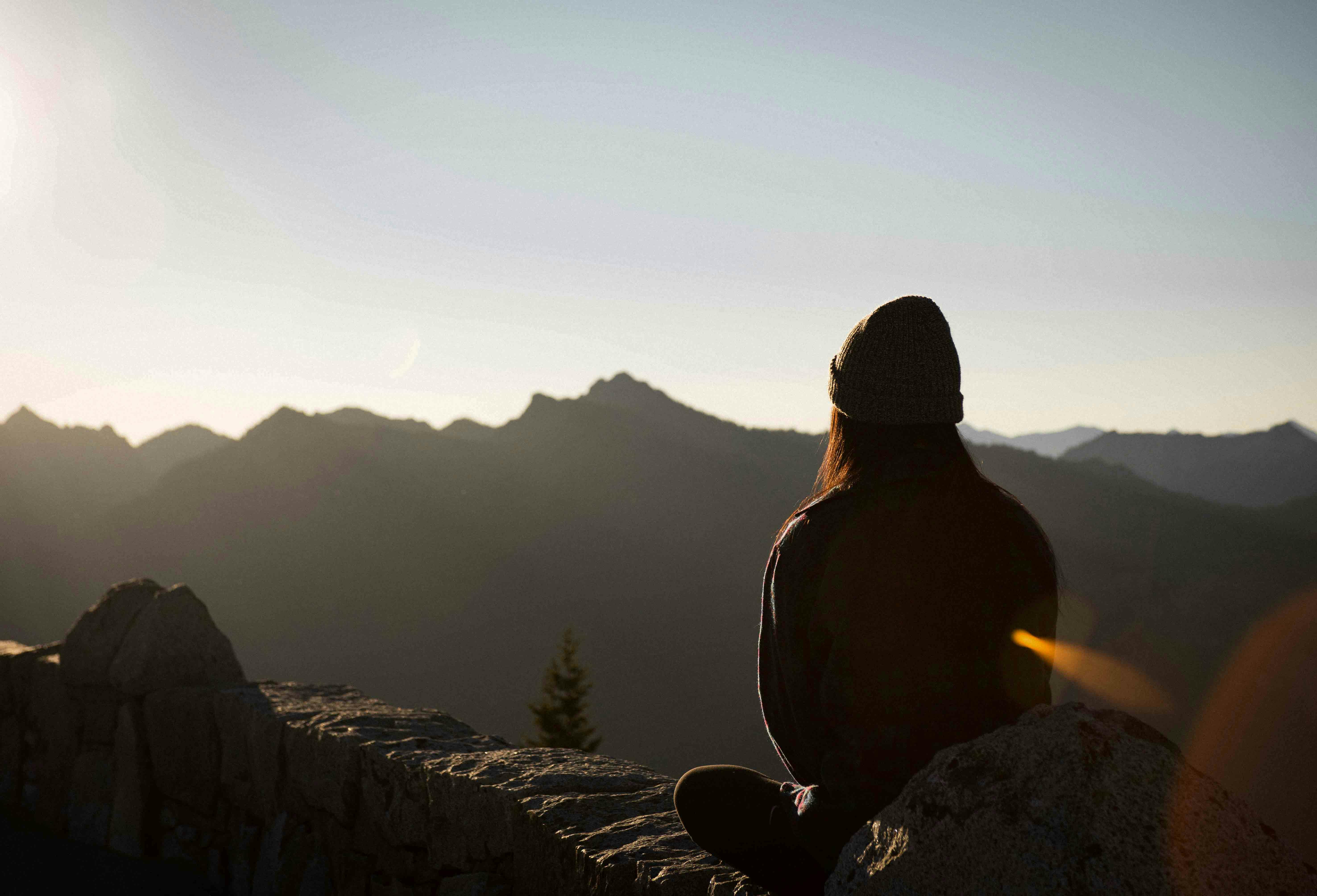 Woman sitting on mountain meditating during a beautiful sunrise.