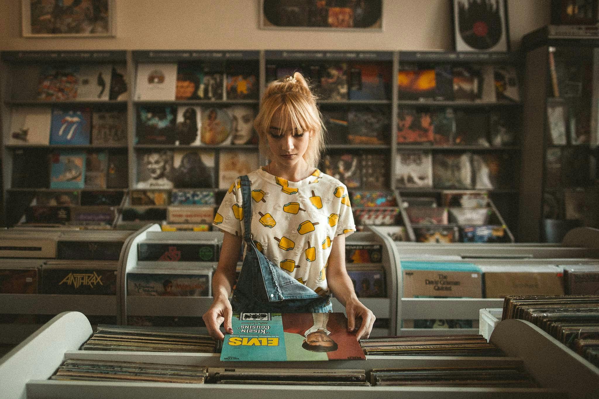 Caucasian woman holding a vinyl in an old, vintage record store.
