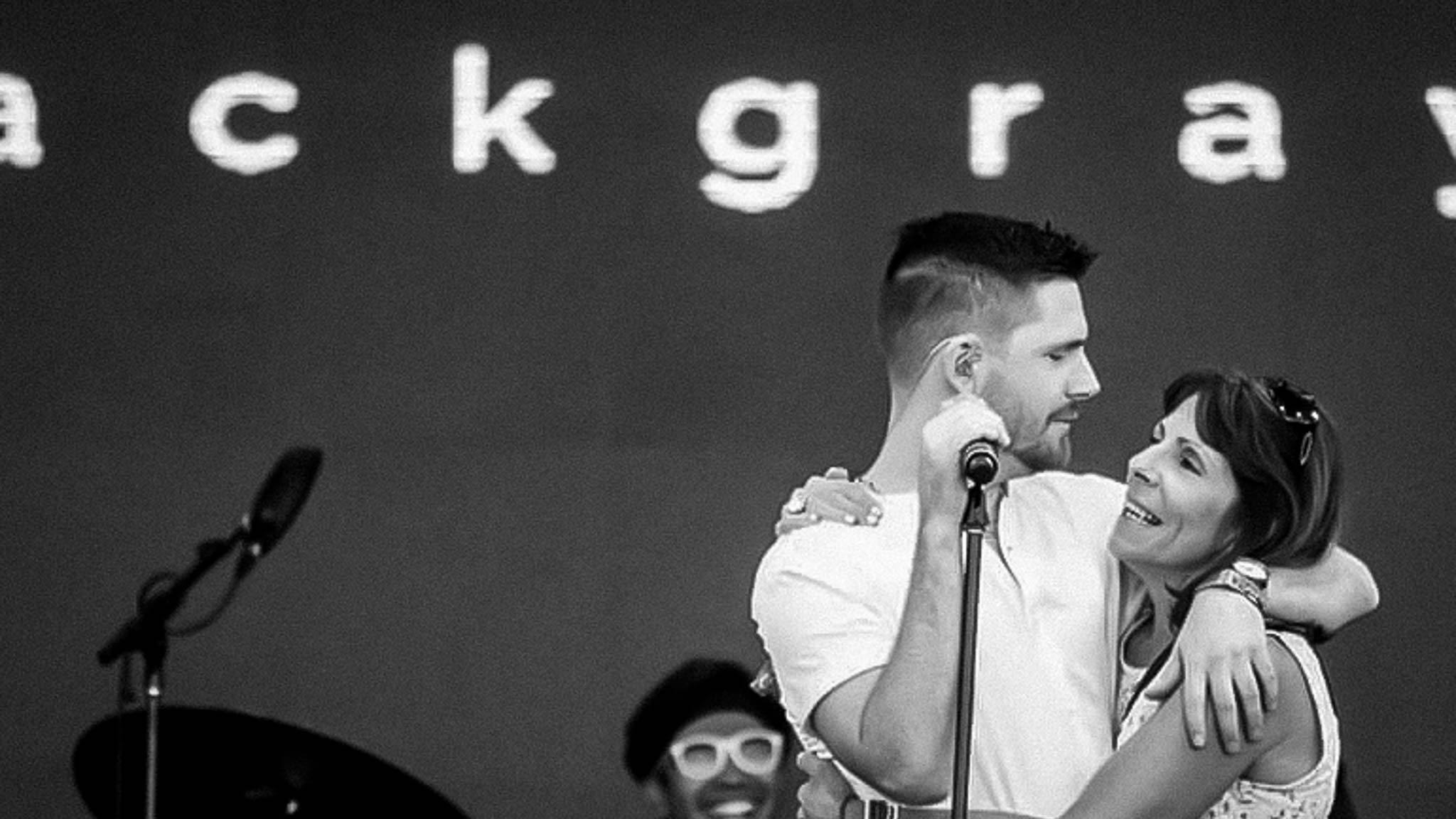 Zack Gray live on stage looking fondly upon his mother.