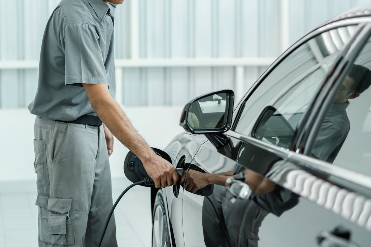 Senior asian Technician is charging the electric car or EV in service center for maintainance, Eco-friendly alternative energy concept