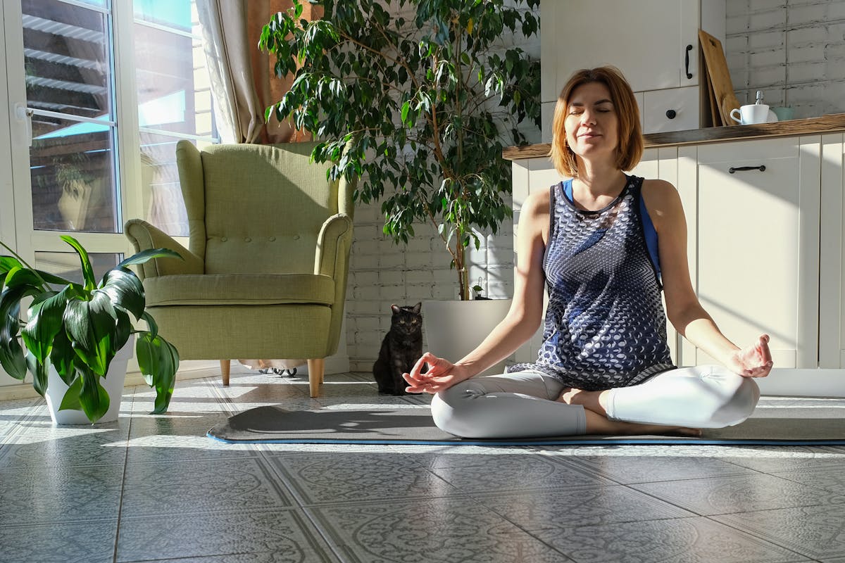 Middle aged woman practicing meditation at home, calm senior middle aged lady in lotus pose doing yoga for mental balance breathing air relaxing