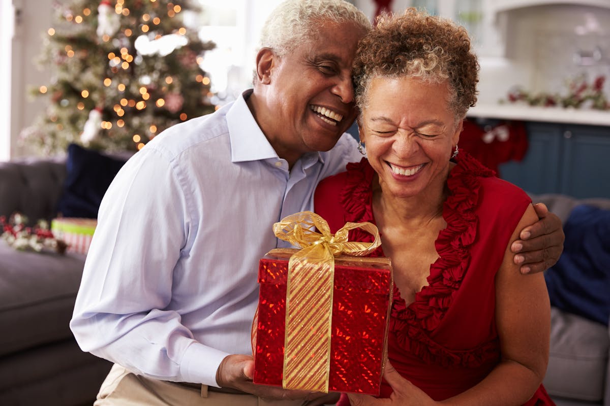 Senior Couple Exchanging Christmas Gifts At Home