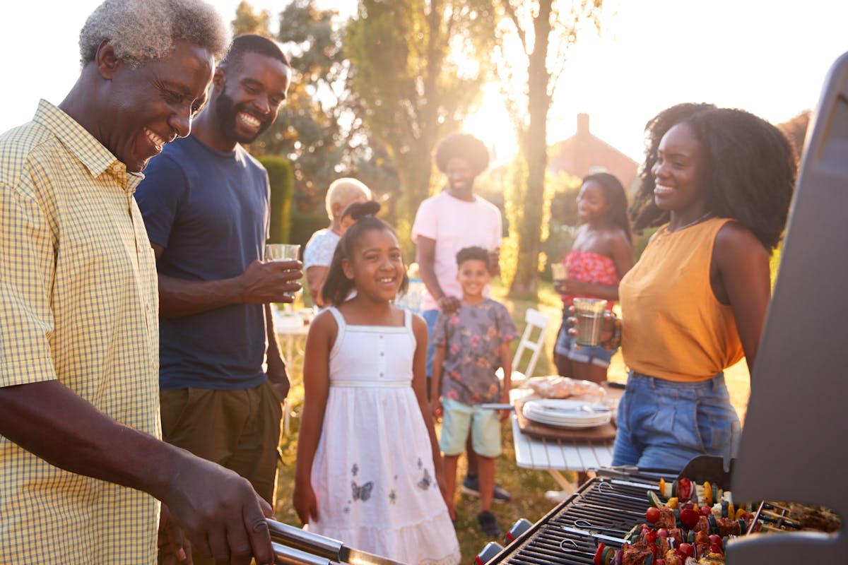 Multi generation family barbecue, grandad grilling