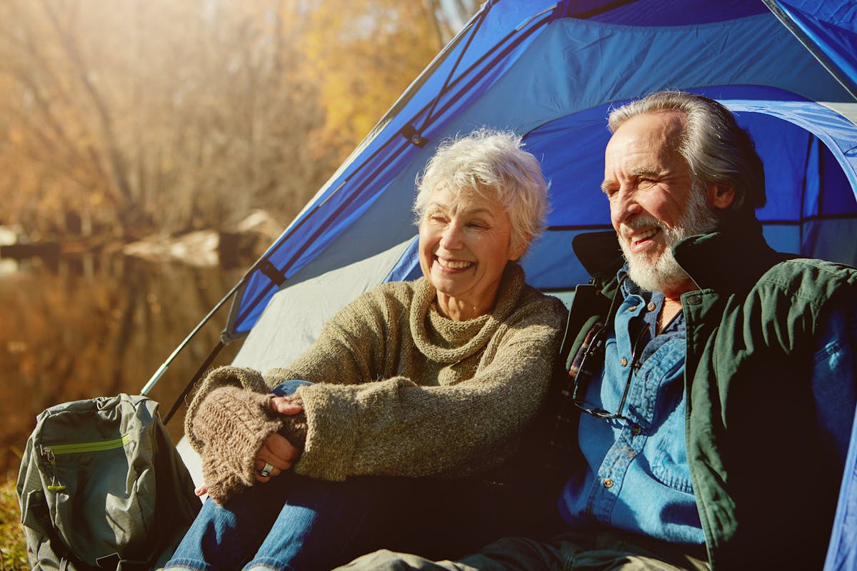 Old couple, tent and camping with nature, sunshine and vacation with hobby, retirement and field. Outdoor, senior man or mature woman with holiday, getaway trip or relax with weekend break and love