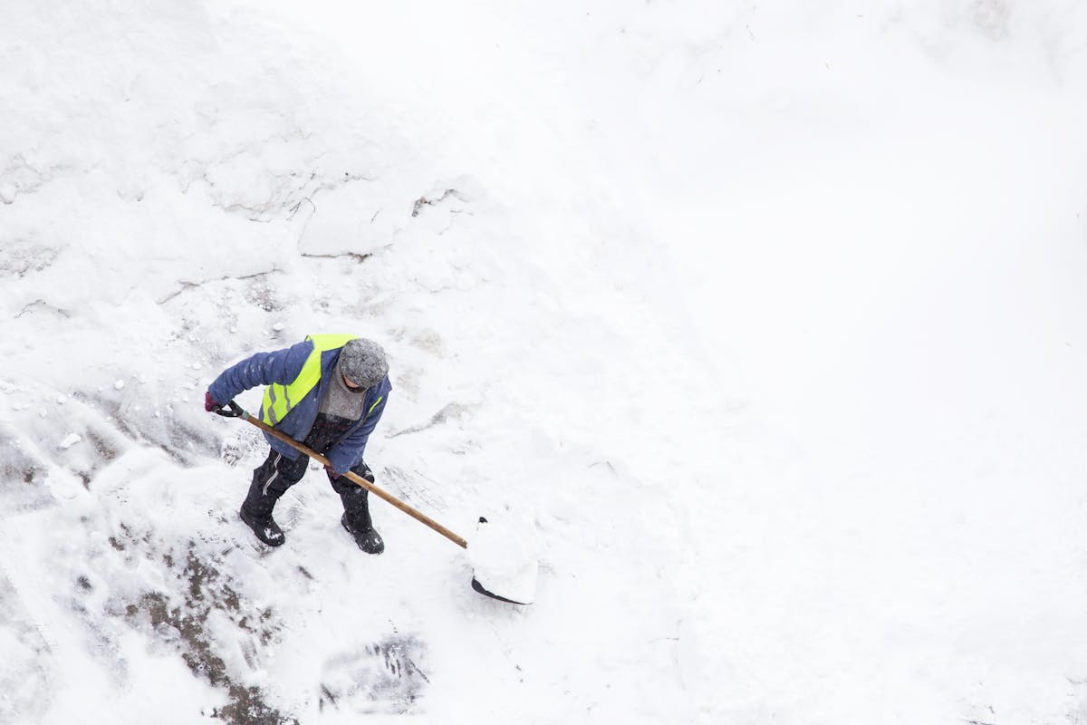 Man shoveling snow after snowfall and blizzard, copy space. Top view of snow clearance