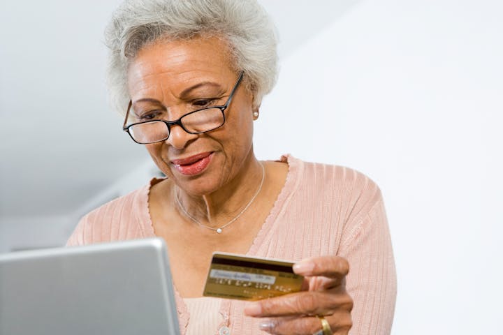 African American senior woman shopping online using laptop and credit card