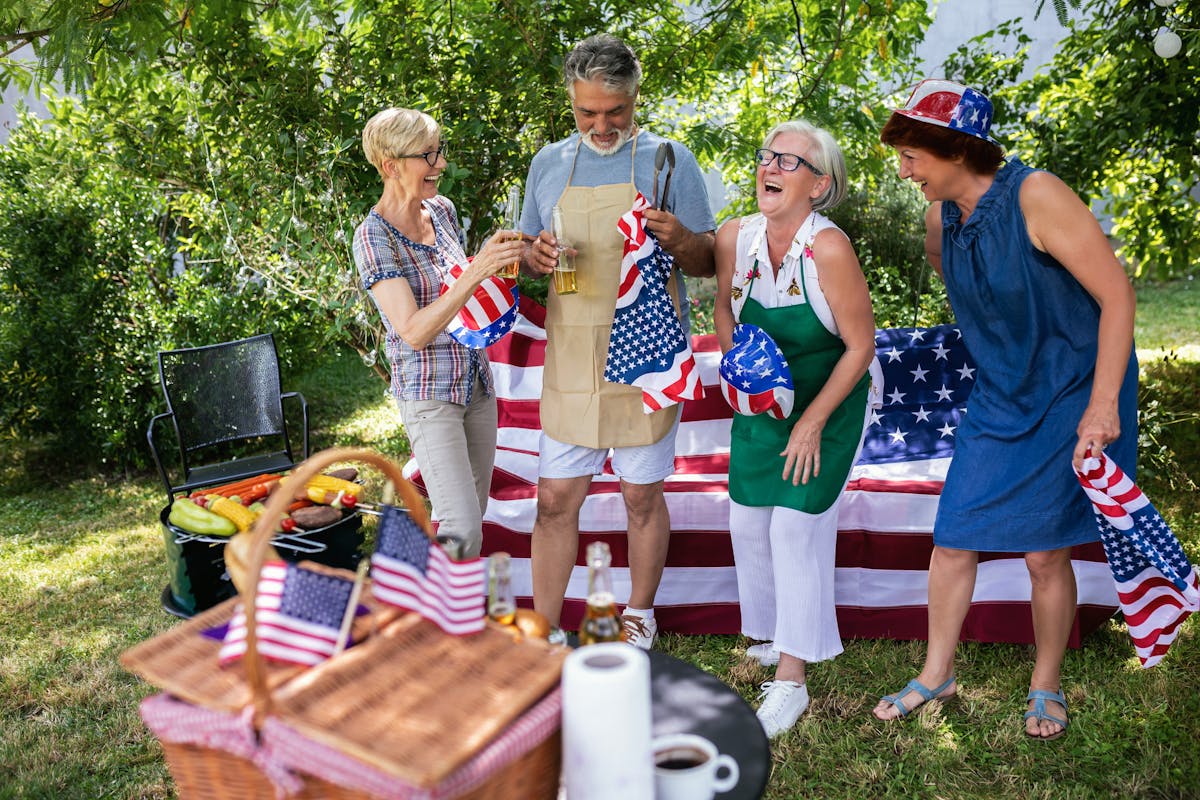 A group of elderly people celebrates the 4th of July in a backyard while making barbeque.