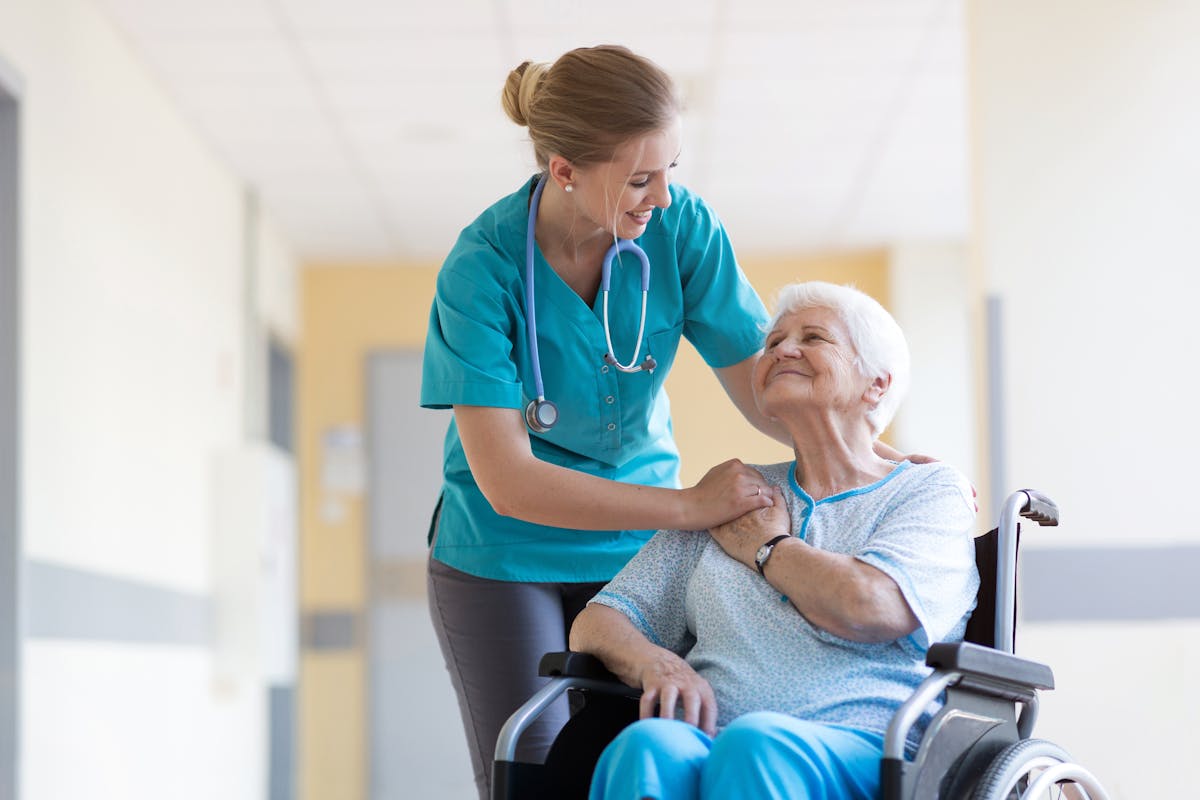 Senior woman in wheelchair with nurse in hospital
