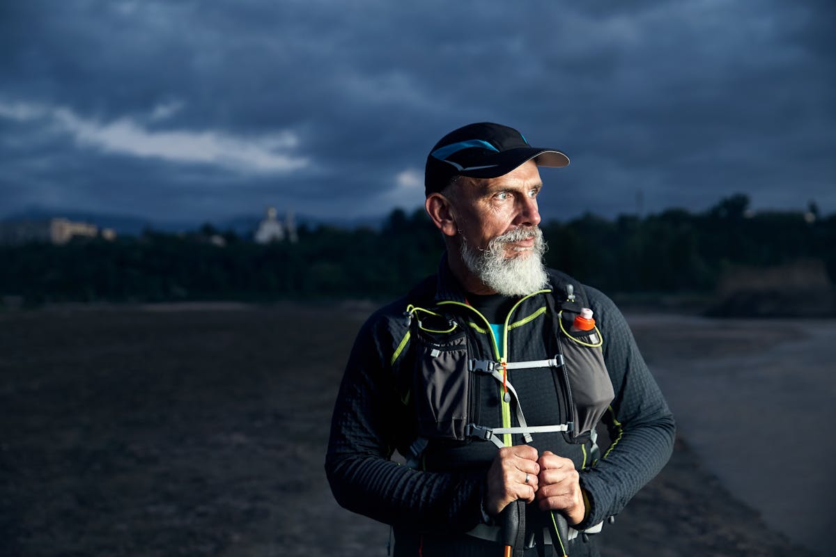 Old athlete with grey beard running after dark