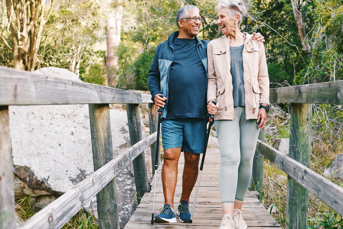 Relax, senior or couple of friends hiking, walking or trekking for freedom, exercise or fitness in nature forest. Interracial, travel or happy woman enjoys bonding time with healthy elderly partner