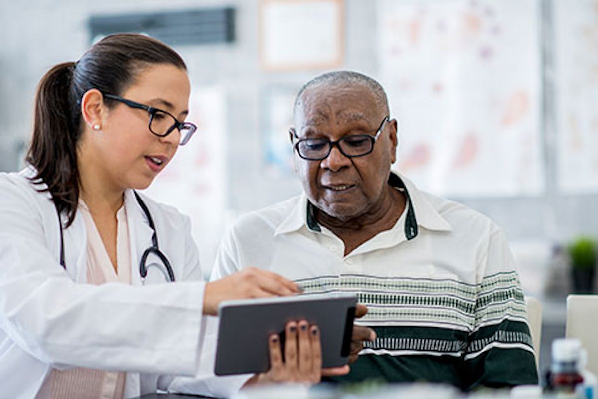 healthcare setting where a female doctor or medical professional is consulting with an older male patient