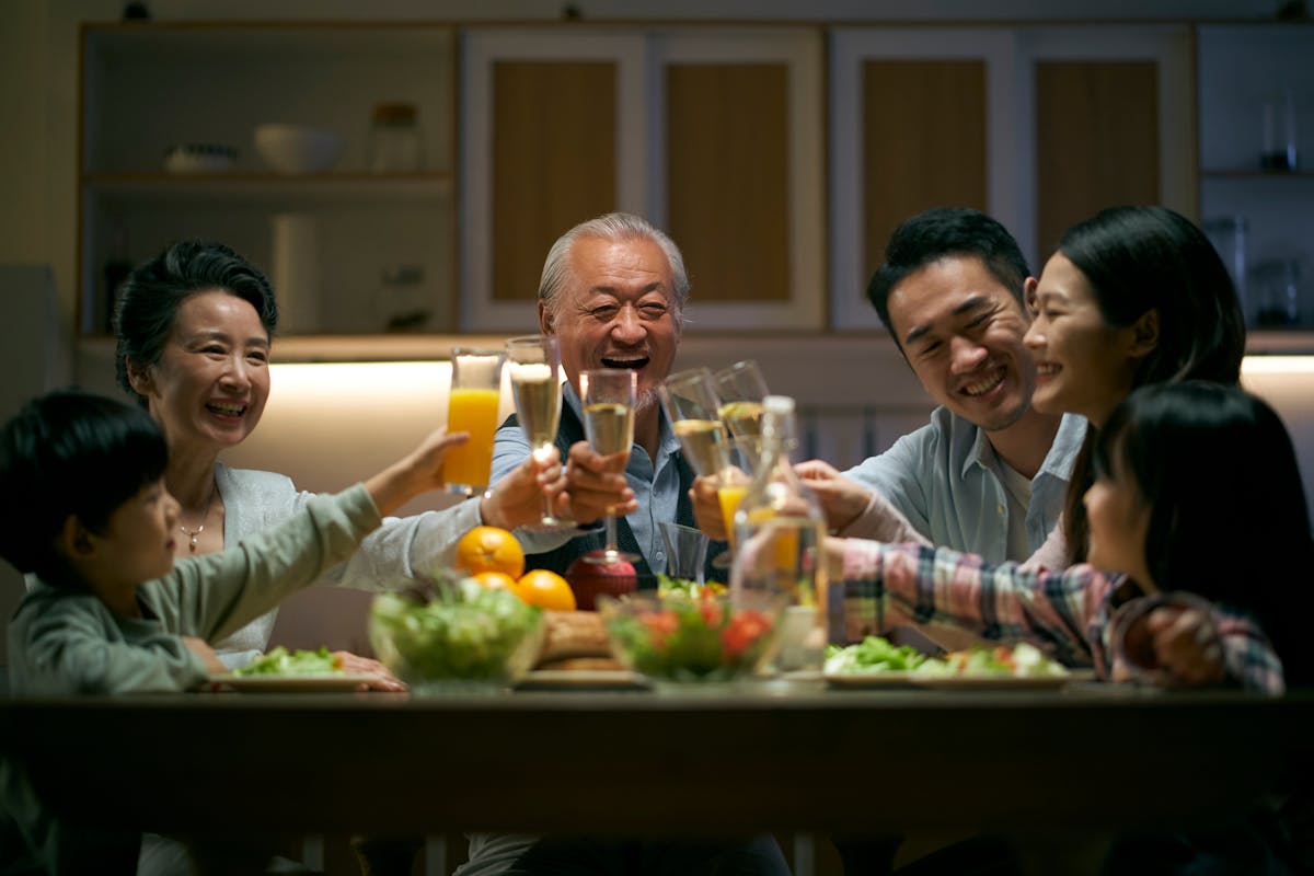 three generation asian family toasting while having dinner together
