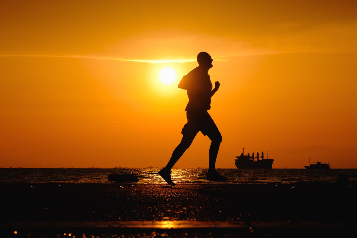 Silhouette of man running along the road during the sunset