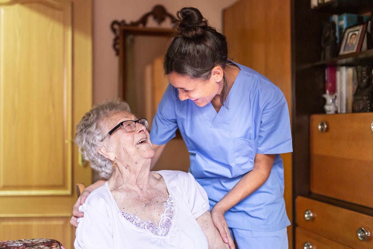 Happy Senior woman laughing. with her caregiver at home. Senior home care concept.