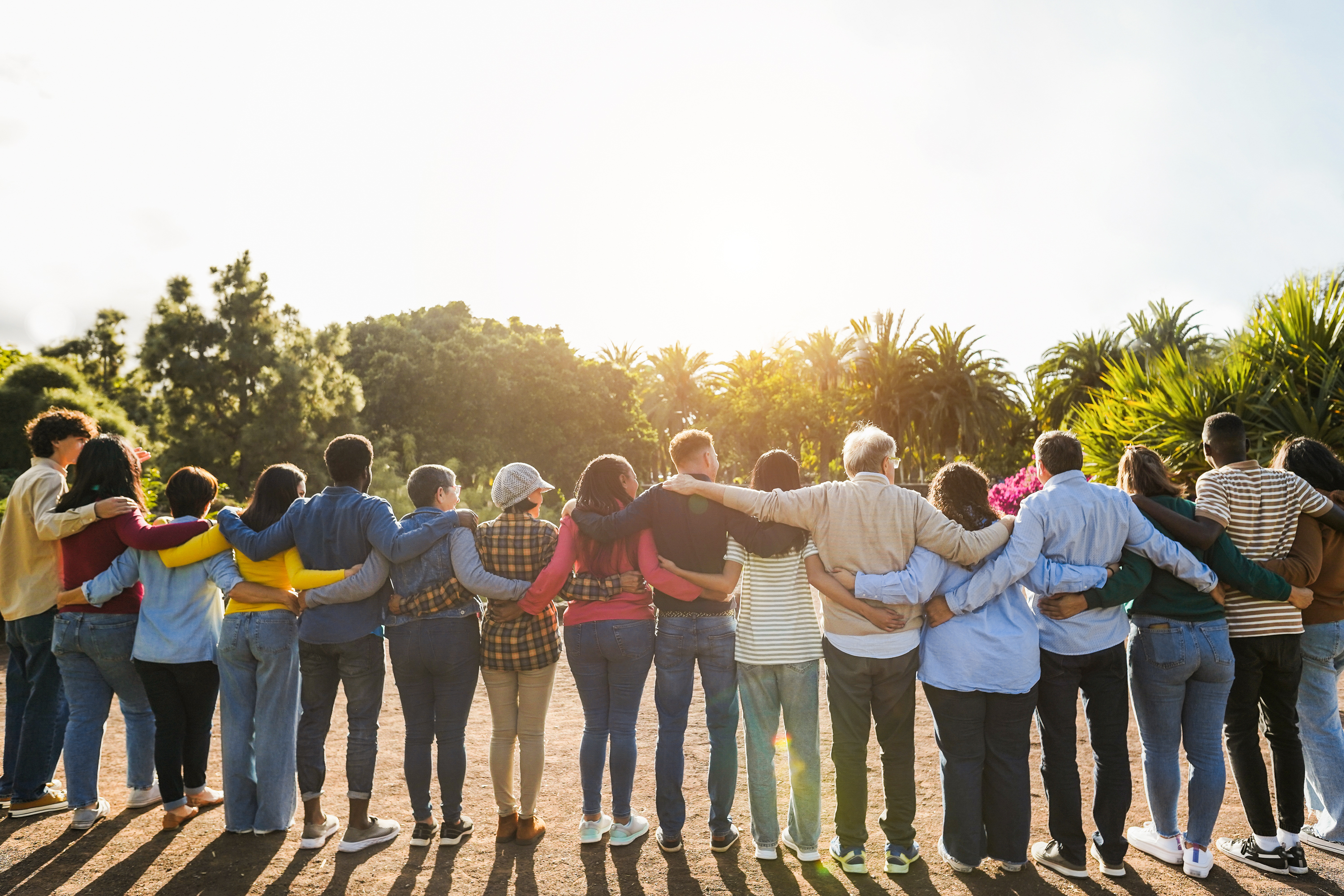 group of people together with arms around each other looking at the sun