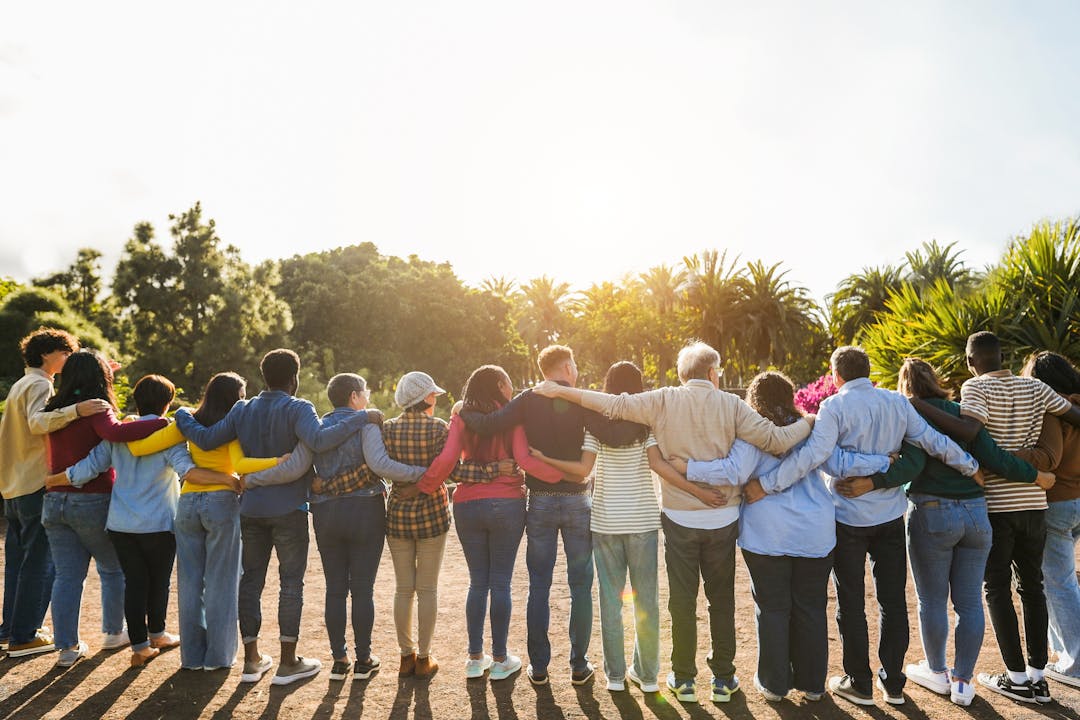 group of people together with arms around each other looking at the sun