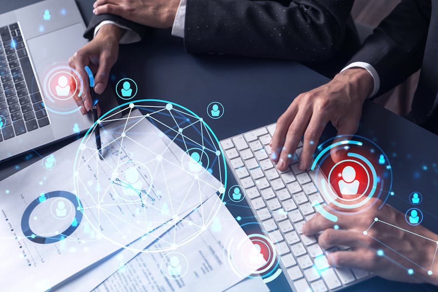 two people on their laptop and looking at papers analysing