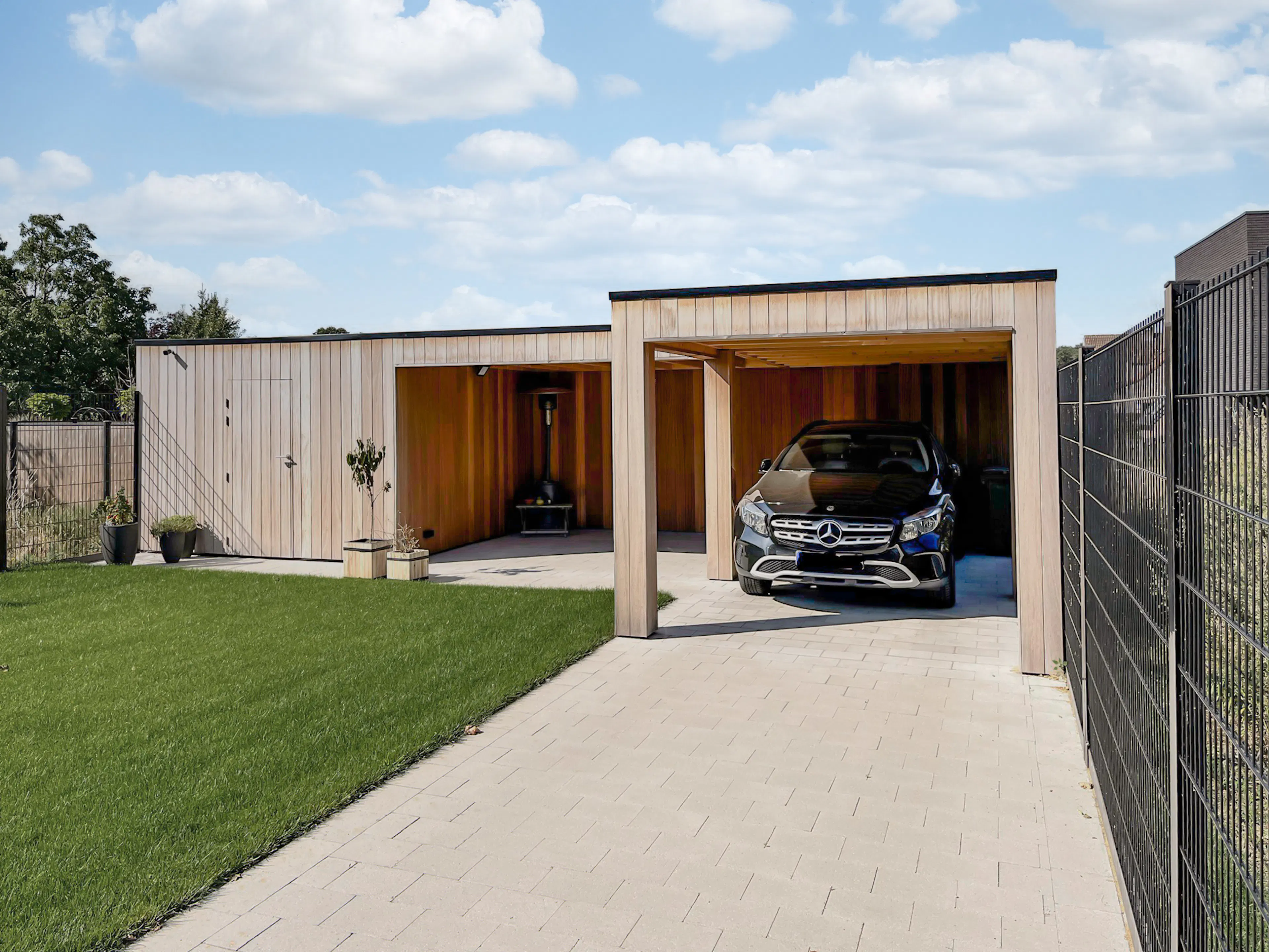 Moderne houten carport op maat met plat dak, overdekt terras en berging in hardhout.