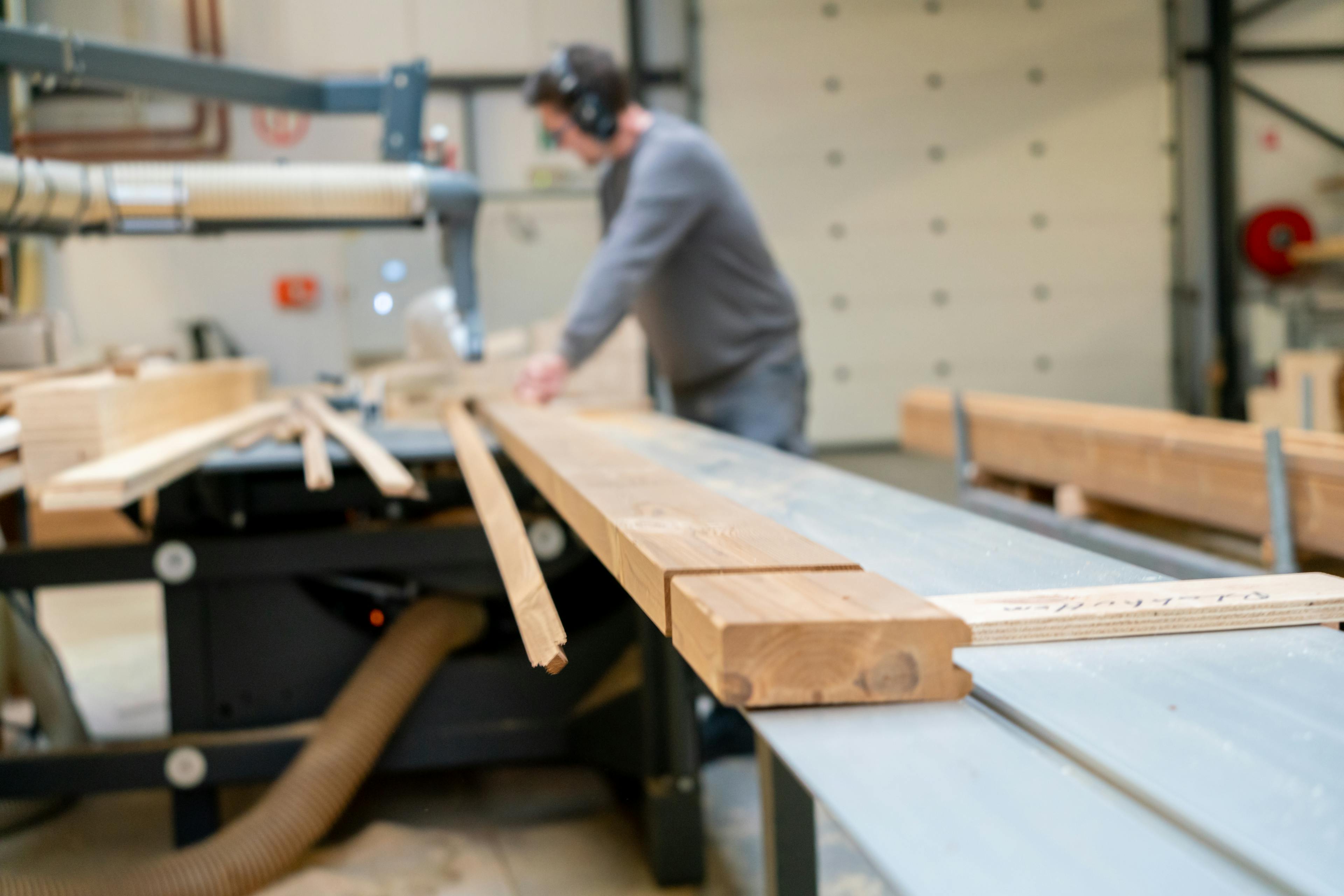 Man die hout op maat snijd in een werkruimte