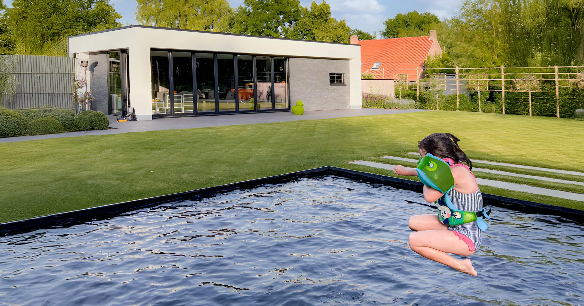Klein meisje dat in een zwembad spring met in de achtergrond een poolhouse