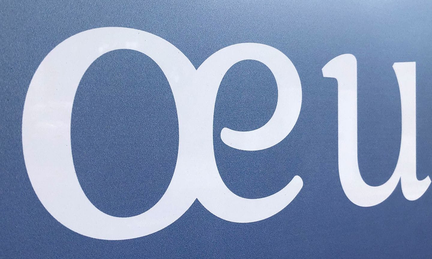 gros plan du détail de la typographie "œ" blanc sur fond dégradé bleu