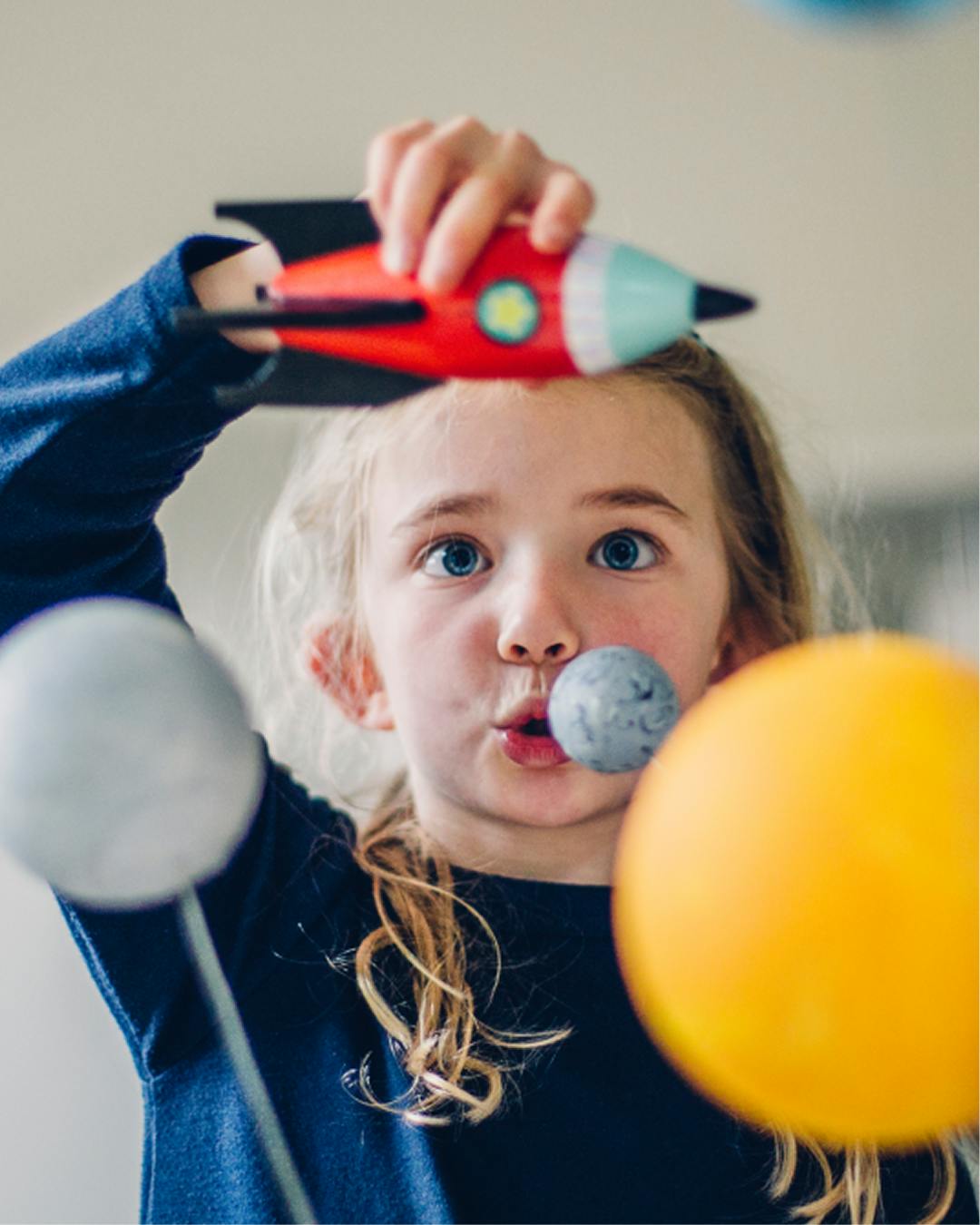 Teneo girl playing with rocket in front of planets