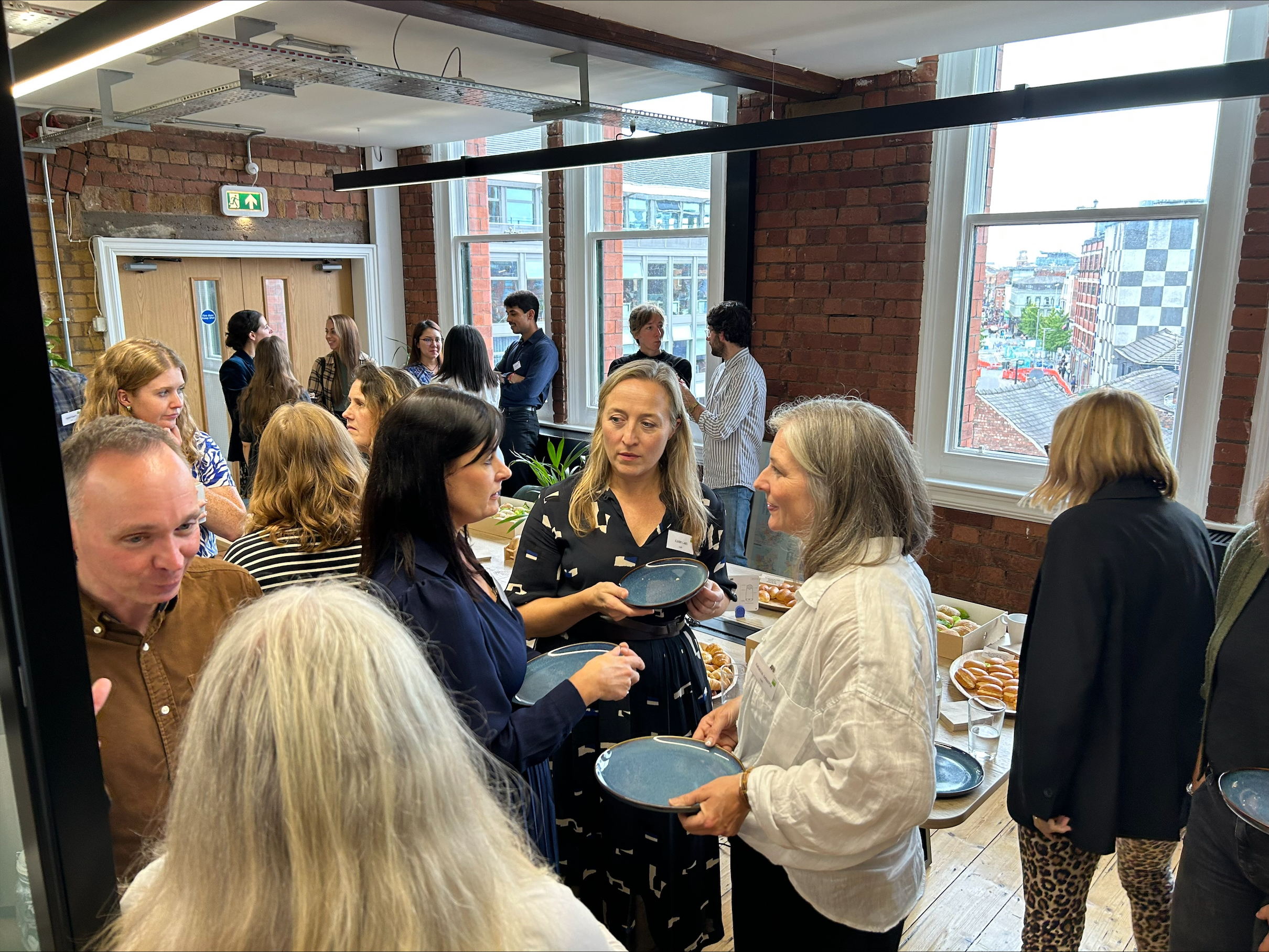 A group of people talking and holding plates of food