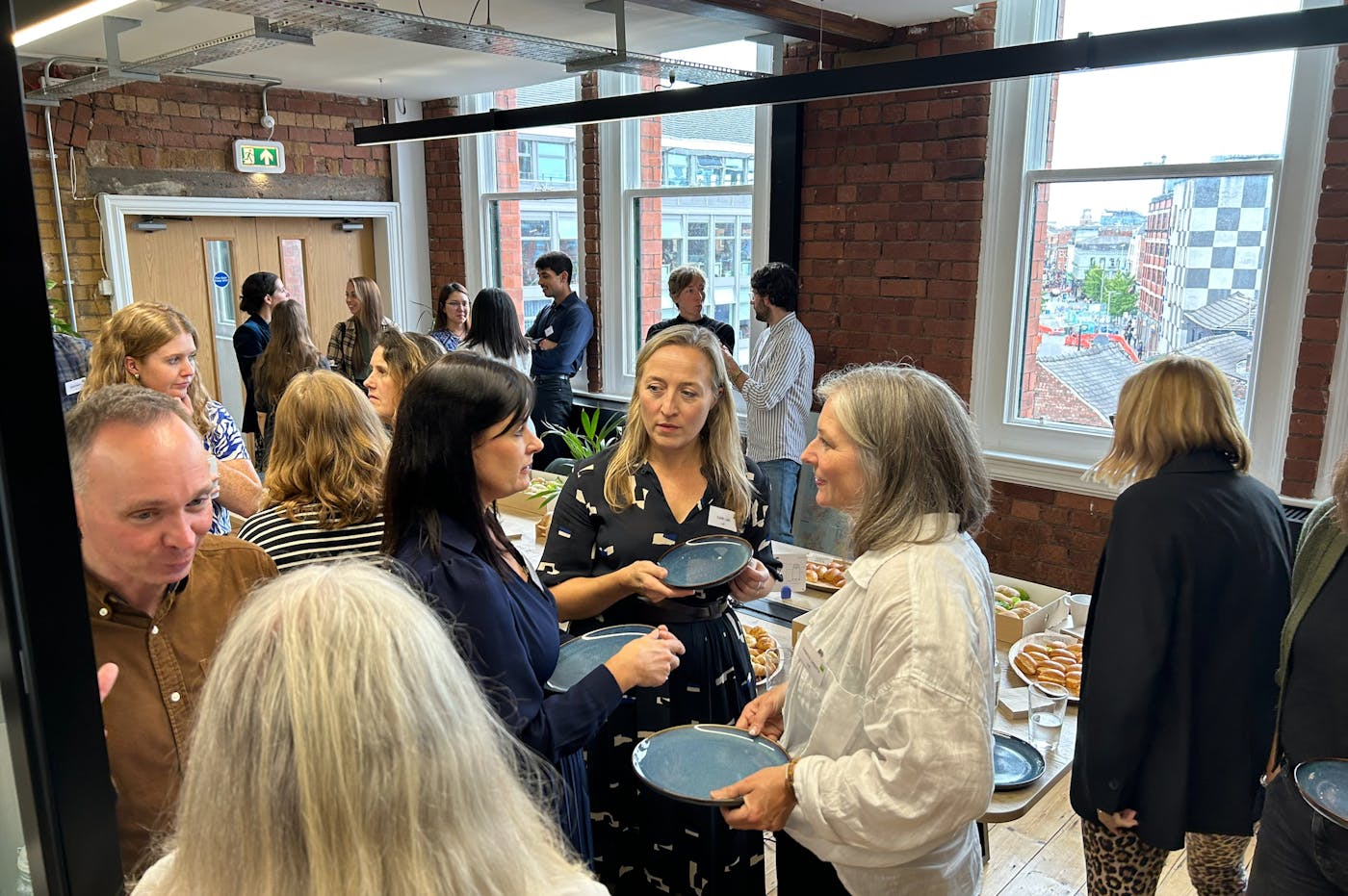 A group of people talking and holding plates of food