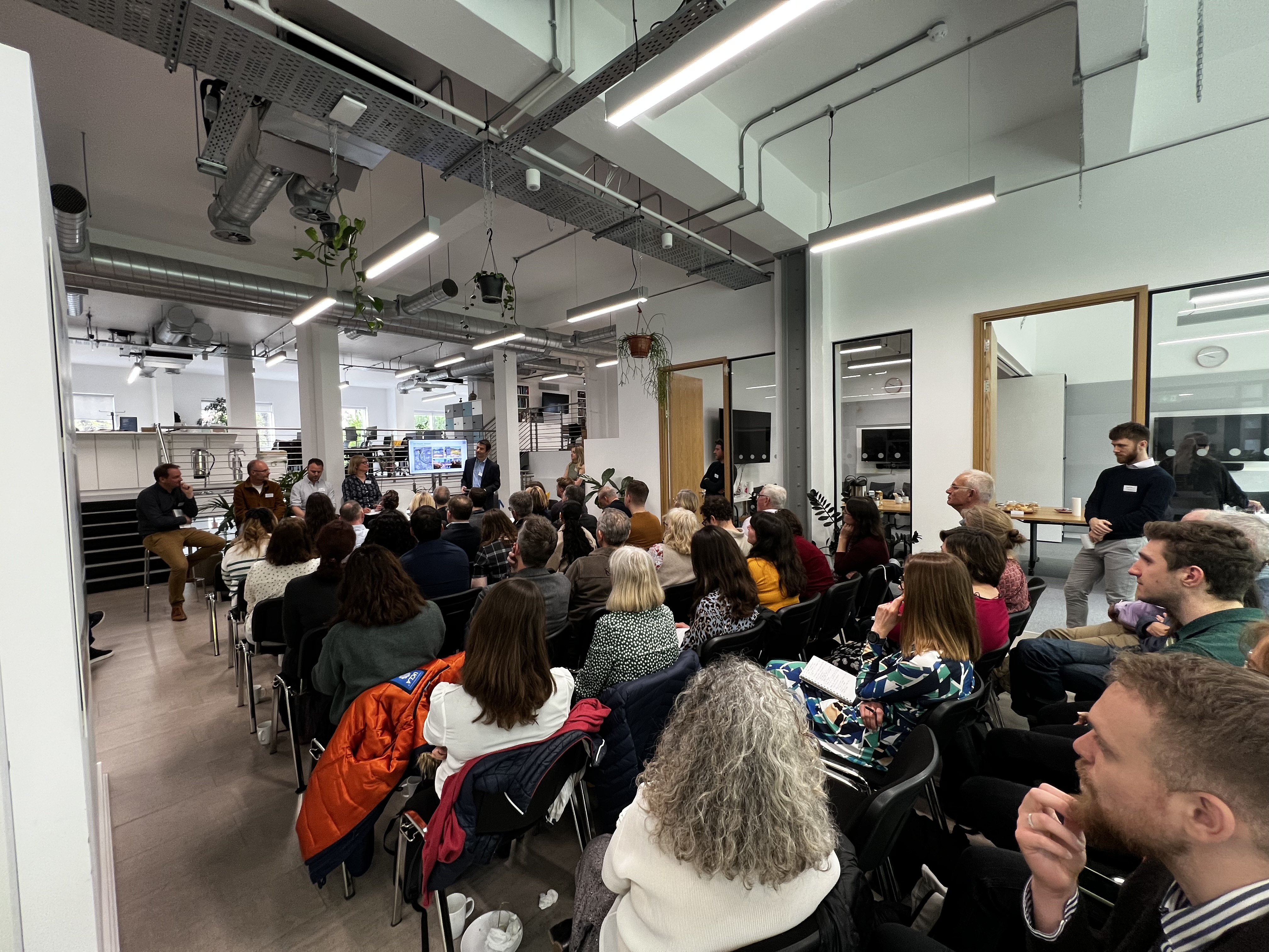 Crowd of people watching a panel discussion comprisng five people