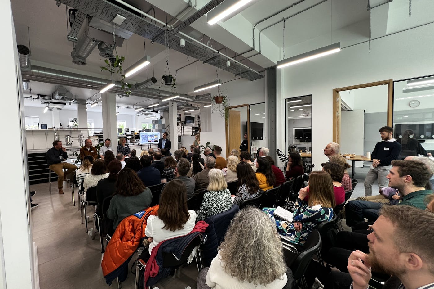 Crowd of people watching a panel discussion comprisng five people