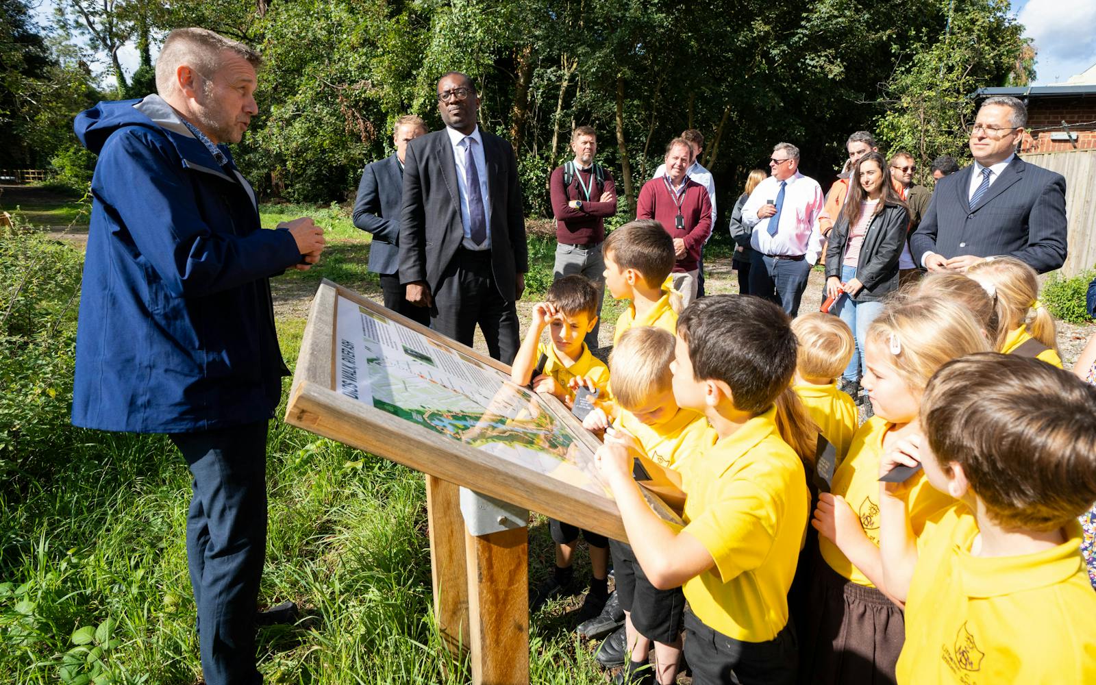 Person talking to group of children in front of information board