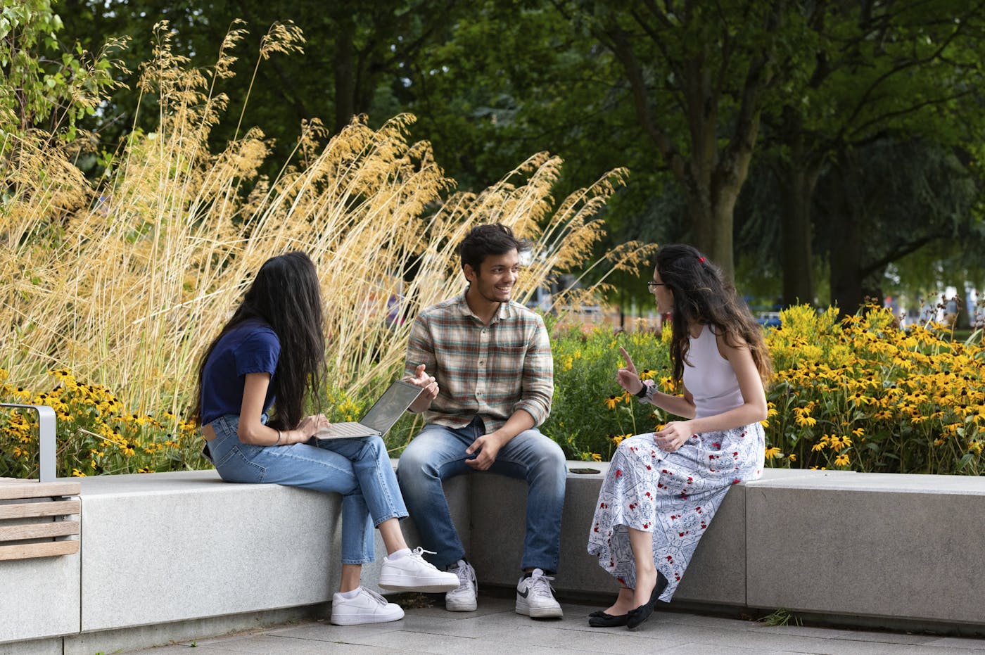 Three people sitting on outdoor stone bench